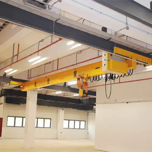 Underhung bridge crane mounted on ceiling structure of concrete workshop